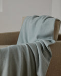 Foxford Achill Cashmere and Lambswool Throw draped over a chair