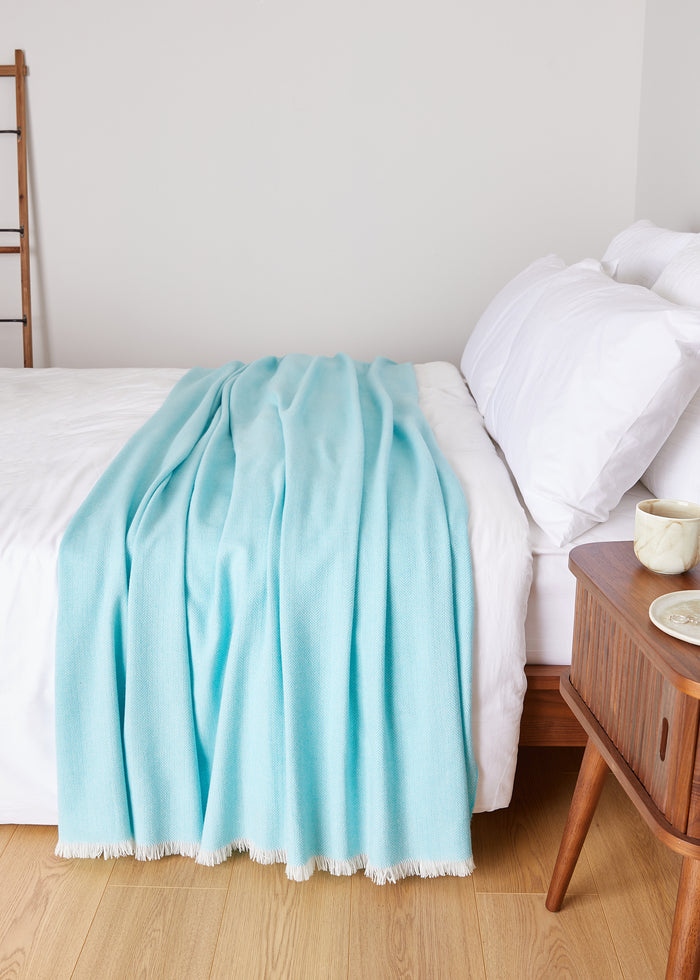 Foxford Extra Large Lambswool Throw Blanket - Turquoise draped over bed